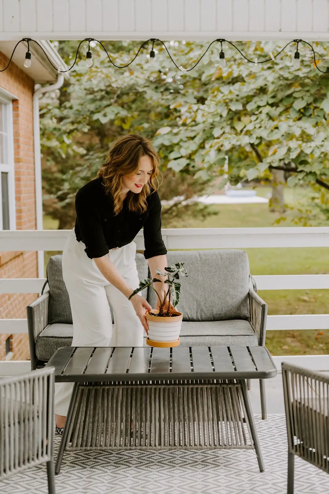 Rachel Ferrell arranging a plant on a covered porch